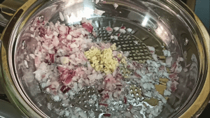 Sautéing chopped onions and garlic in a pan for making spaghetti Bolognese