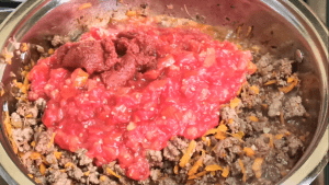 Crushed tomatoes and tomato paste added to meat sauce recipe for spaghetti