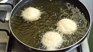 Add the round molded dumplings into the oil and fry until golden brown in color