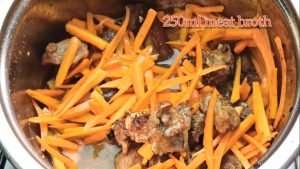 Add meat broth and cook the meat further with carrots