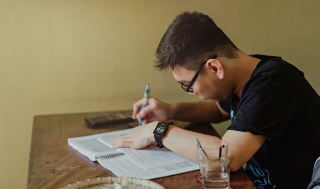 Free Man in Black Shirt Sitting and Writing Stock Photo