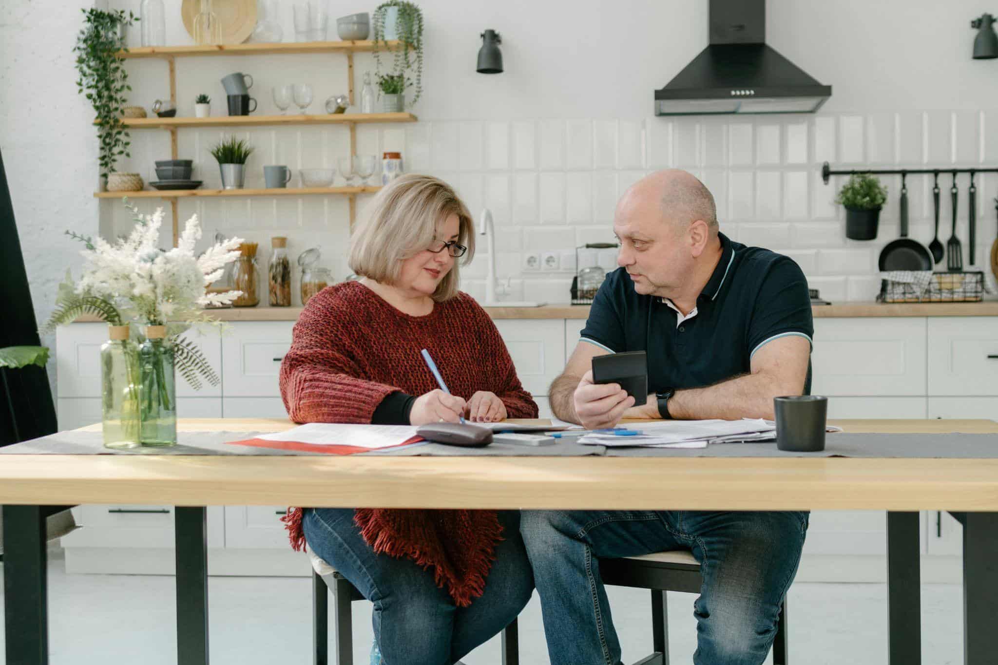 Couple reviewing a pre-approved loan offer at their kitchen table, comparing terms with a calculator