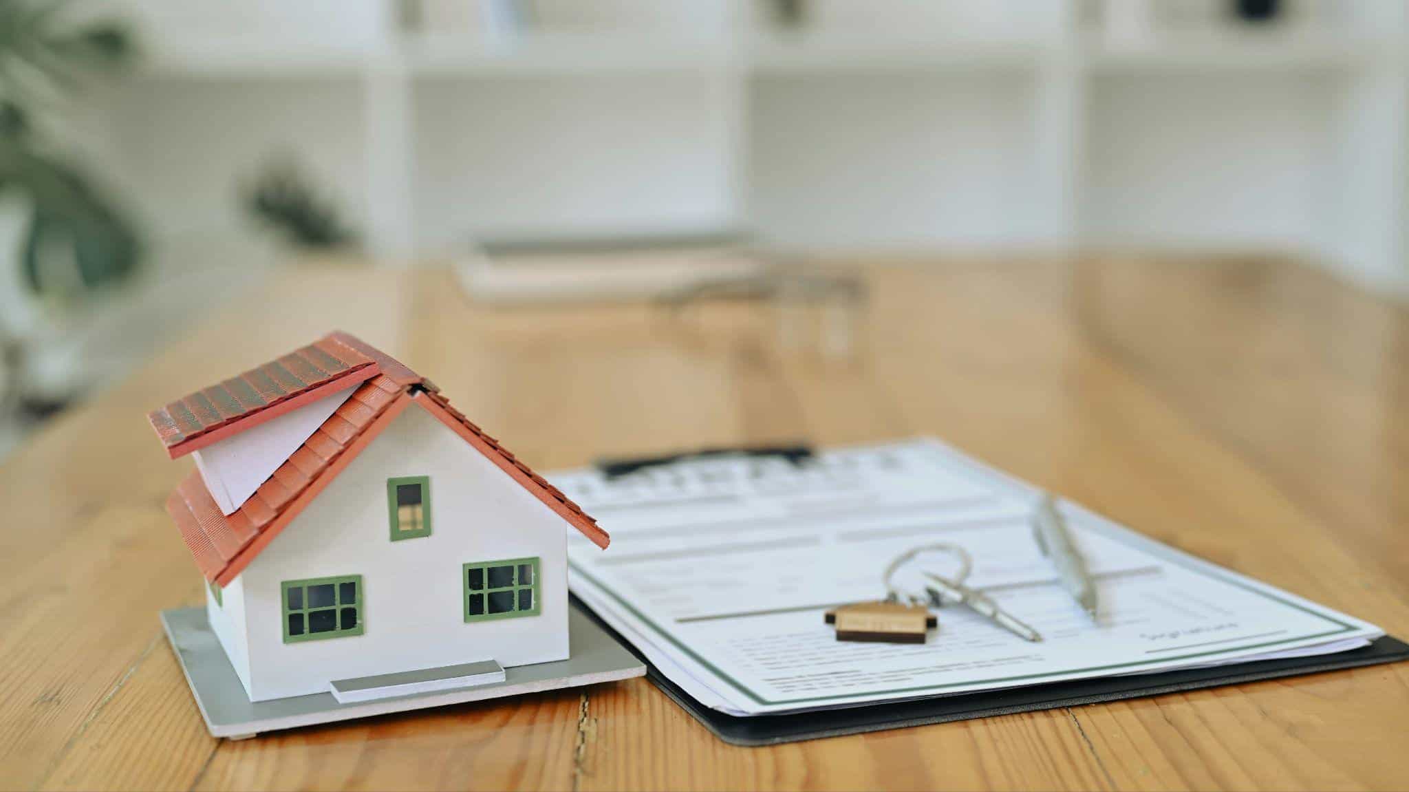Model house, keys and pen on a home warranty agreement ready for signing
